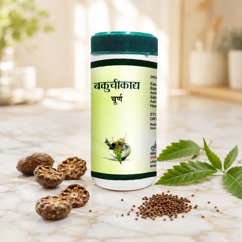 Bakuchikadya Churna jar on white marble with dried amla, neem leaves and bakuchi seeds